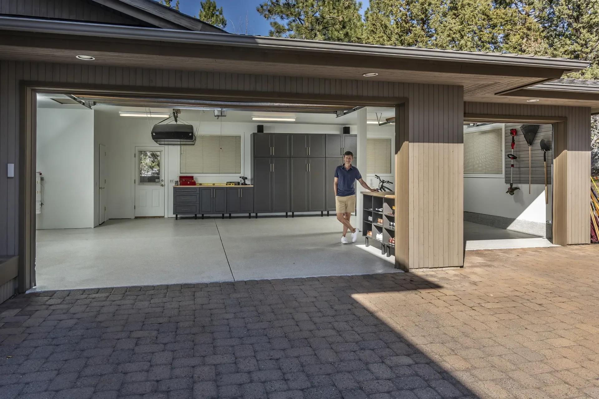 Open garage with a person standing by the workbench and kitchen area inside