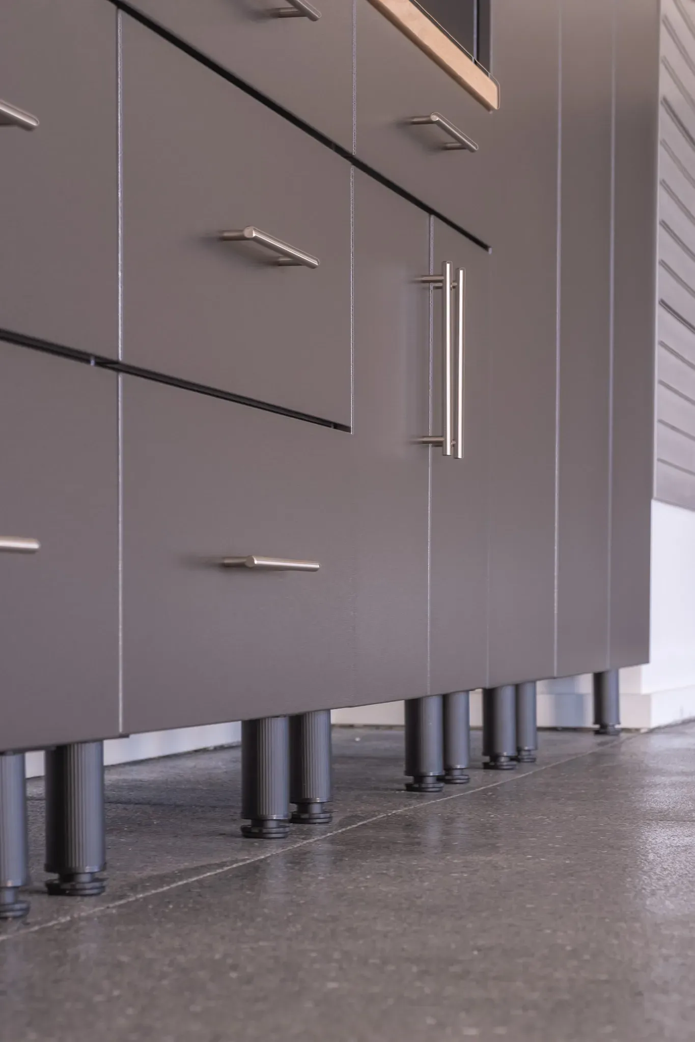 Modern gray kitchen cabinets with silver handles on a speckled floor