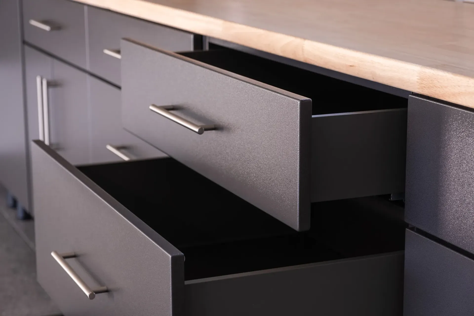Open black drawer with silver handles in a wooden desk