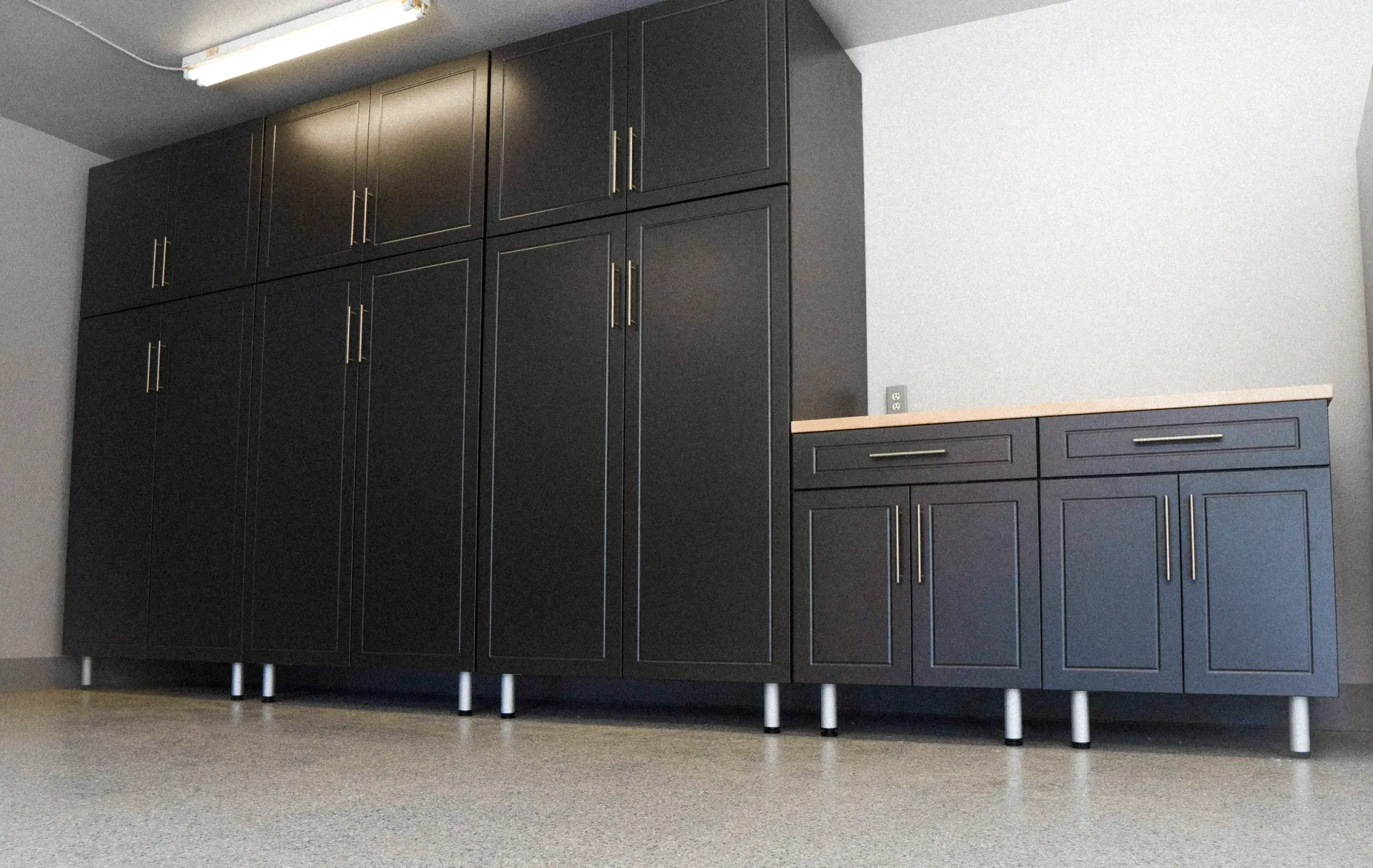 Black cabinets and a dark sideboard against a light wall in a room with a concrete floor.