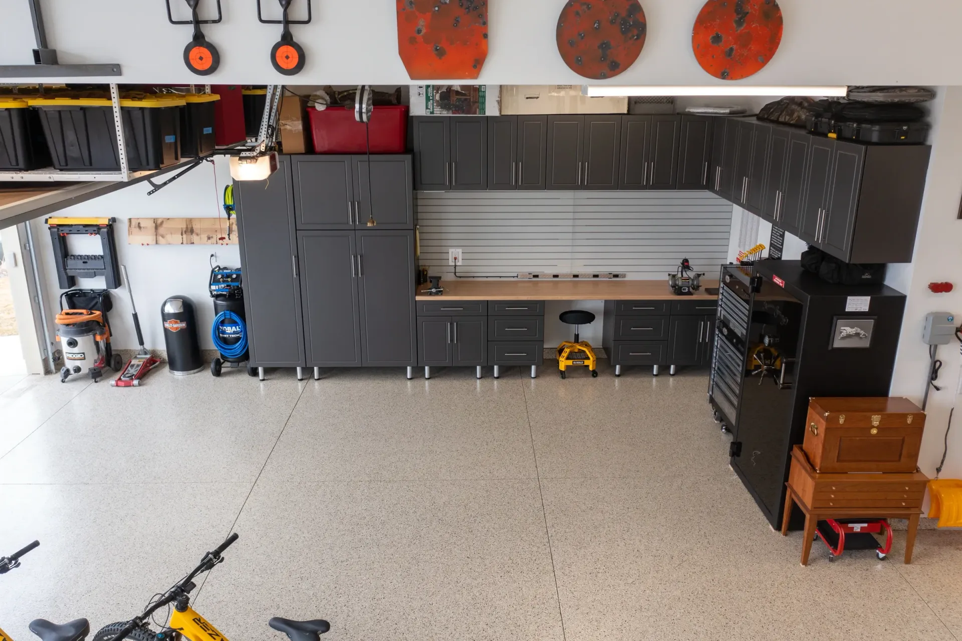 Spacious garage workshop with gray cabinets, a workbench, tools, and a speckled epoxy floor