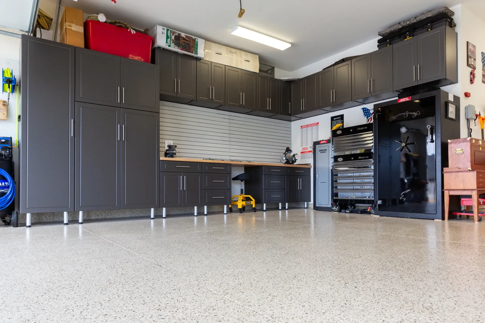 Spacious garage with dark cabinets, workbench, tools, and a speckled epoxy floor.