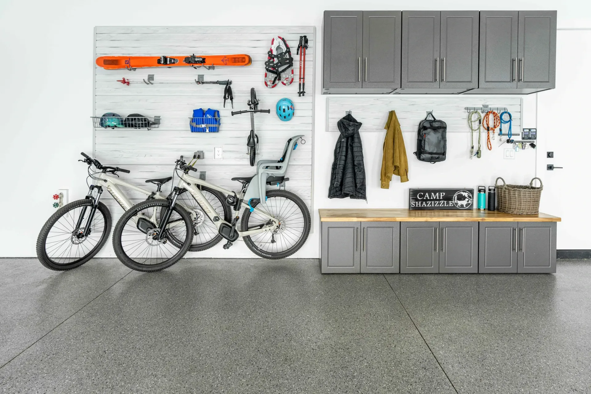 Garage wall with bikes, skis, tools, and gray cabinets organized on a pegboard storage system