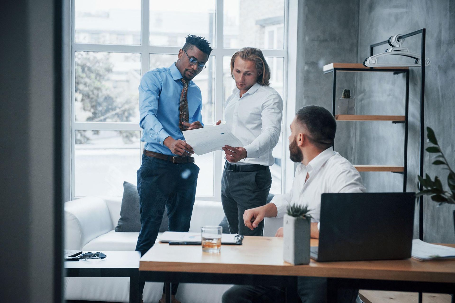 Three coworkers reviewing a document in a modern office meeting room