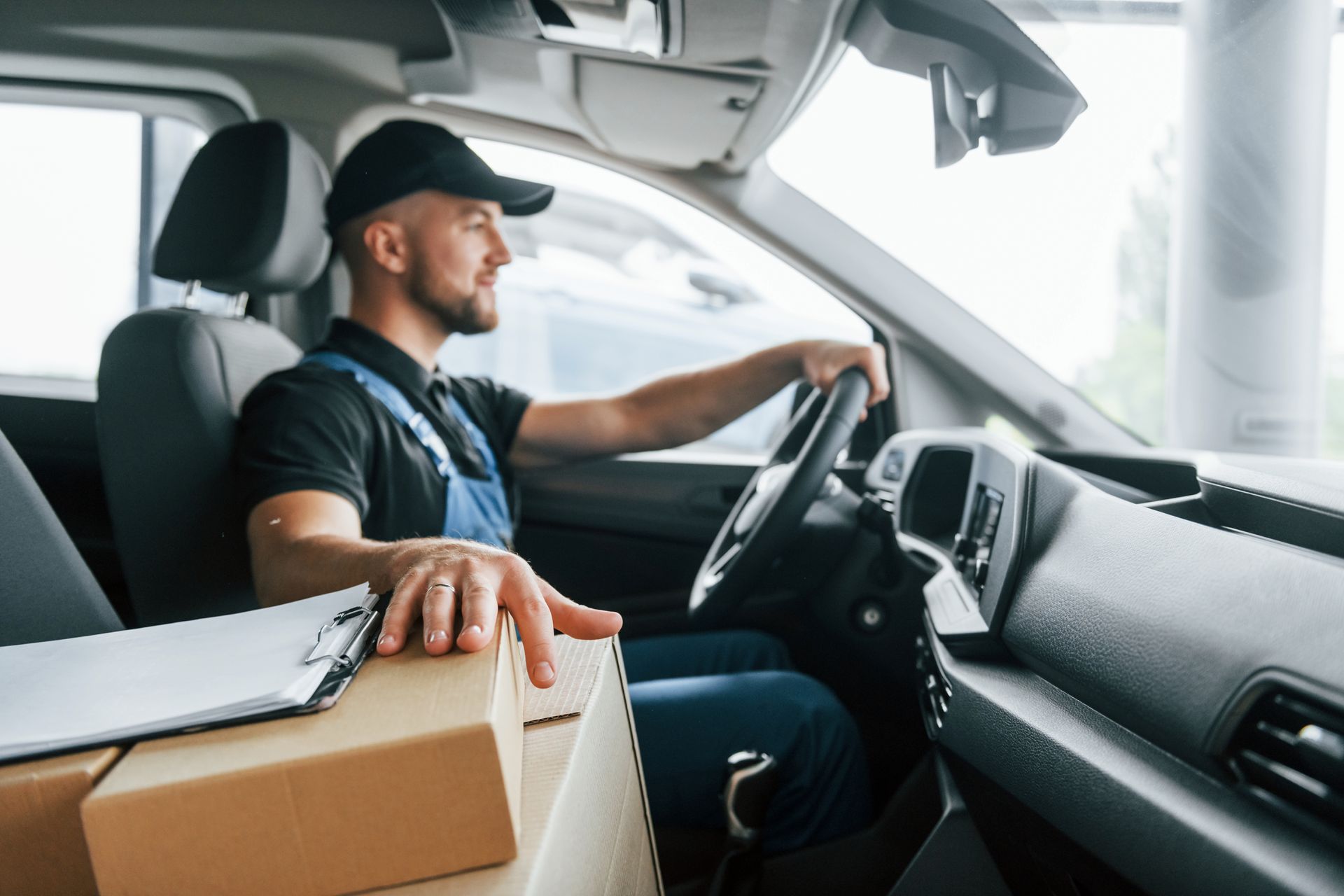 Delivery driver in van with packages, driving and holding the steering wheel