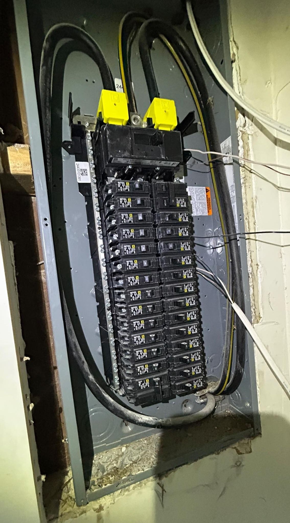 An open electrical panel with multiple circuit breakers and thick black supply cables with yellow capped connectors.