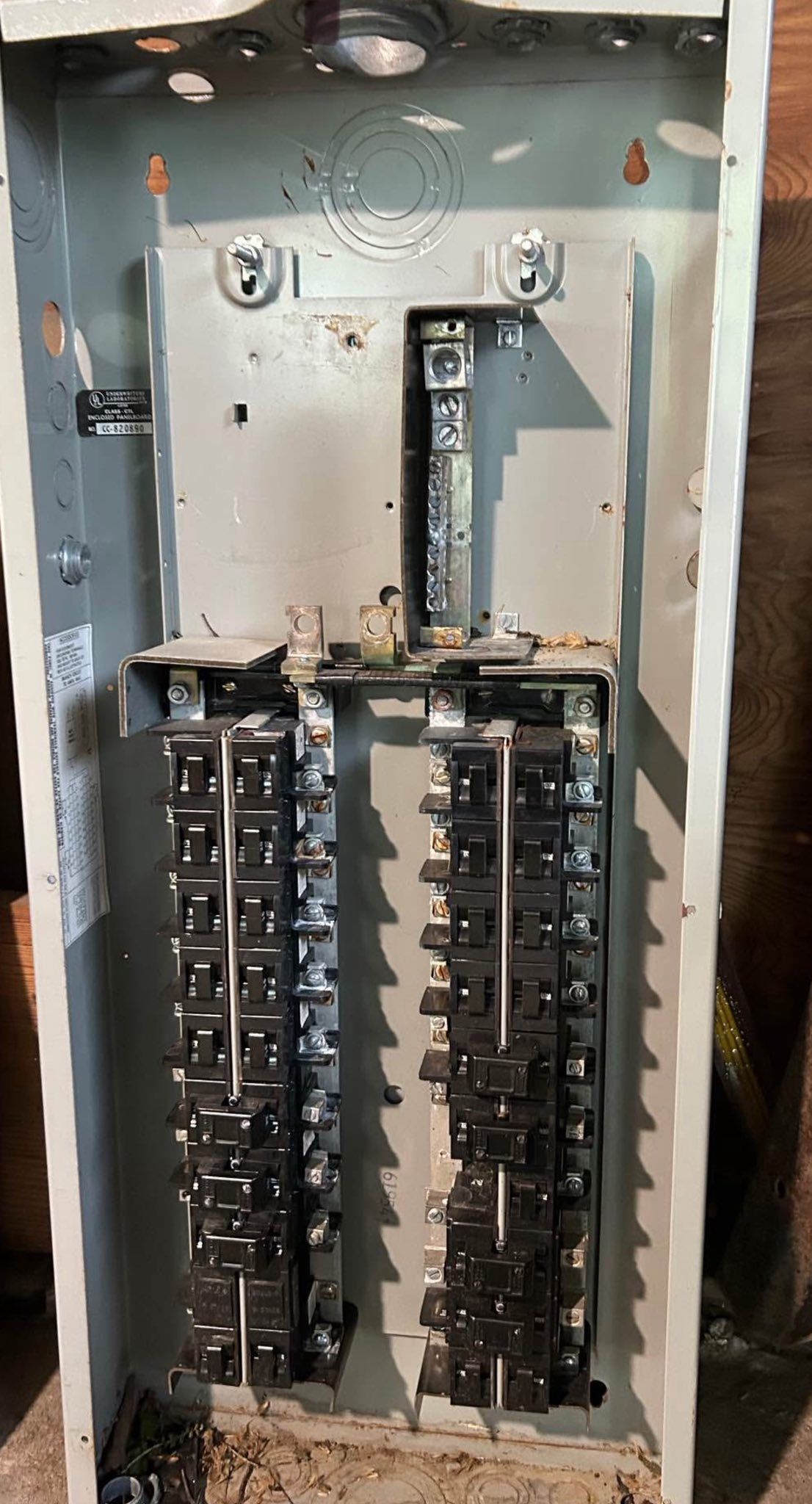 An open electrical service panel showing two vertical rows of circuit breakers inside a gray metal cabinet.