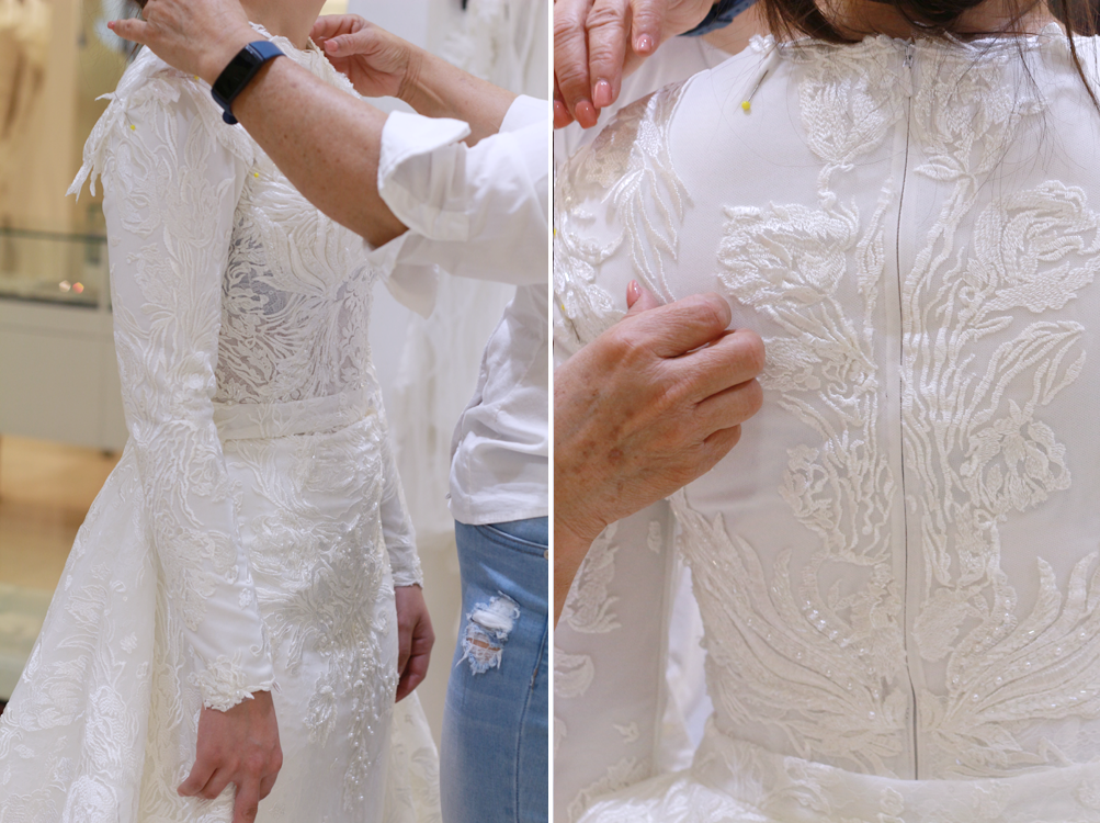 Dressmaker adjusting the back of a white, embellished wedding dress on a person.