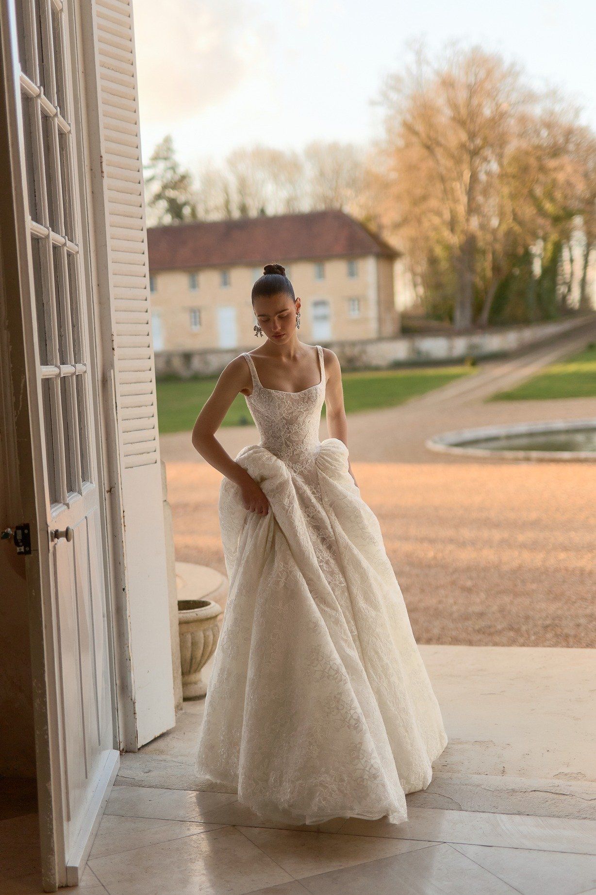 Newlyweds holding hands, exiting a building at night. Bride in satin gown, groom in tuxedo smiling.
