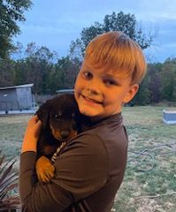 Young boy hugging a Rottweiler puppy