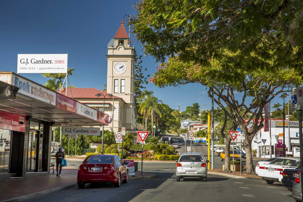 A car is driving down a street in a city with a clock tower in the background.