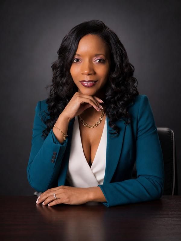 Headshot of Taneka Wilborn, MSN, APRN, ANP-BC, sitting at a table with hand resting under chin