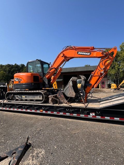 A large orange excavator is sitting on top of a trailer.