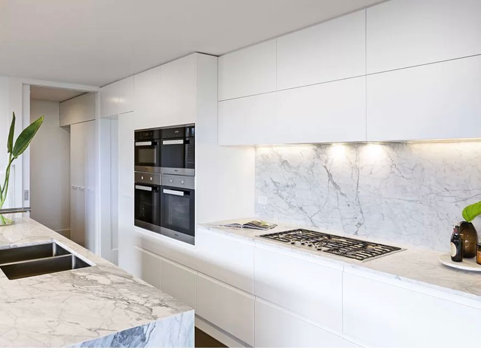 A kitchen with white cabinets and a stove top oven.