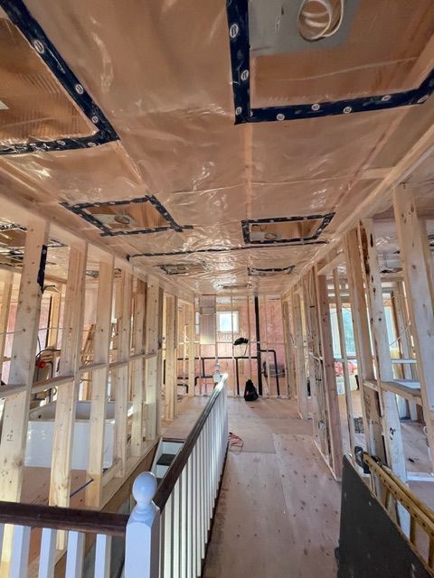 Interior of a building under construction, framed walls and ceiling. Plastic sheeting covers ceiling features.
