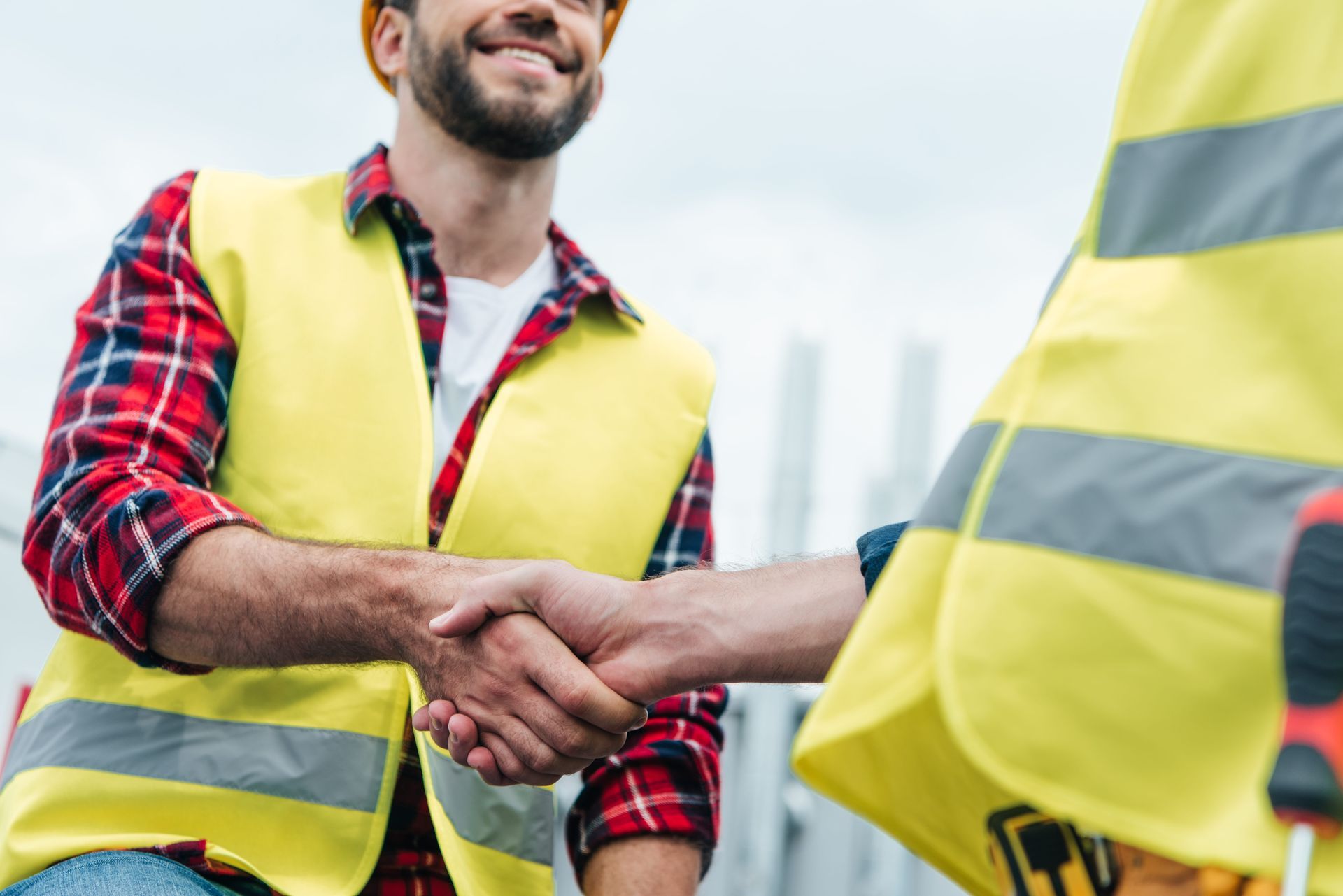 Construction workers in yellow vests shaking hands at a job site