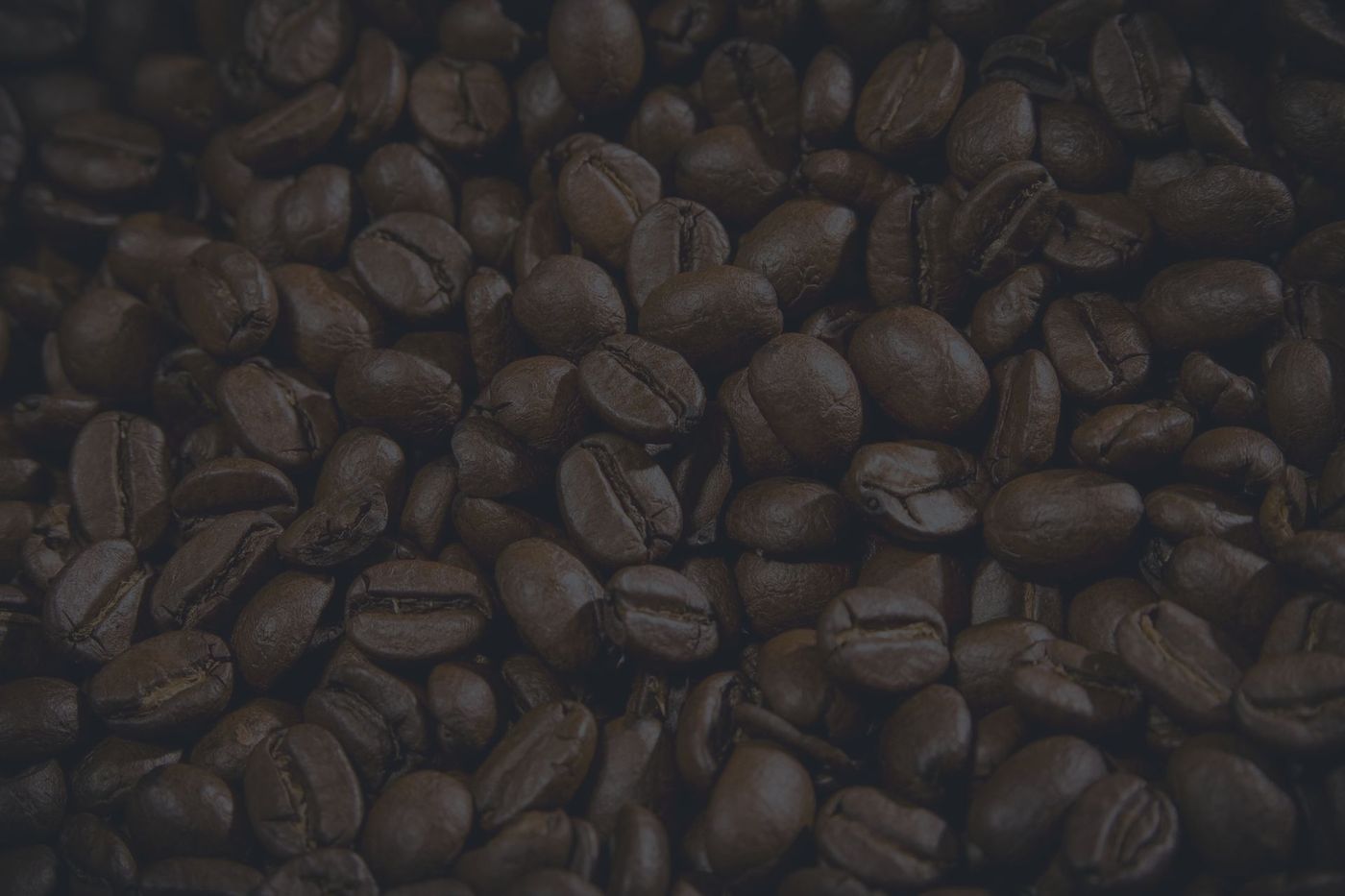 A close up of a pile of coffee beans on a black background.
