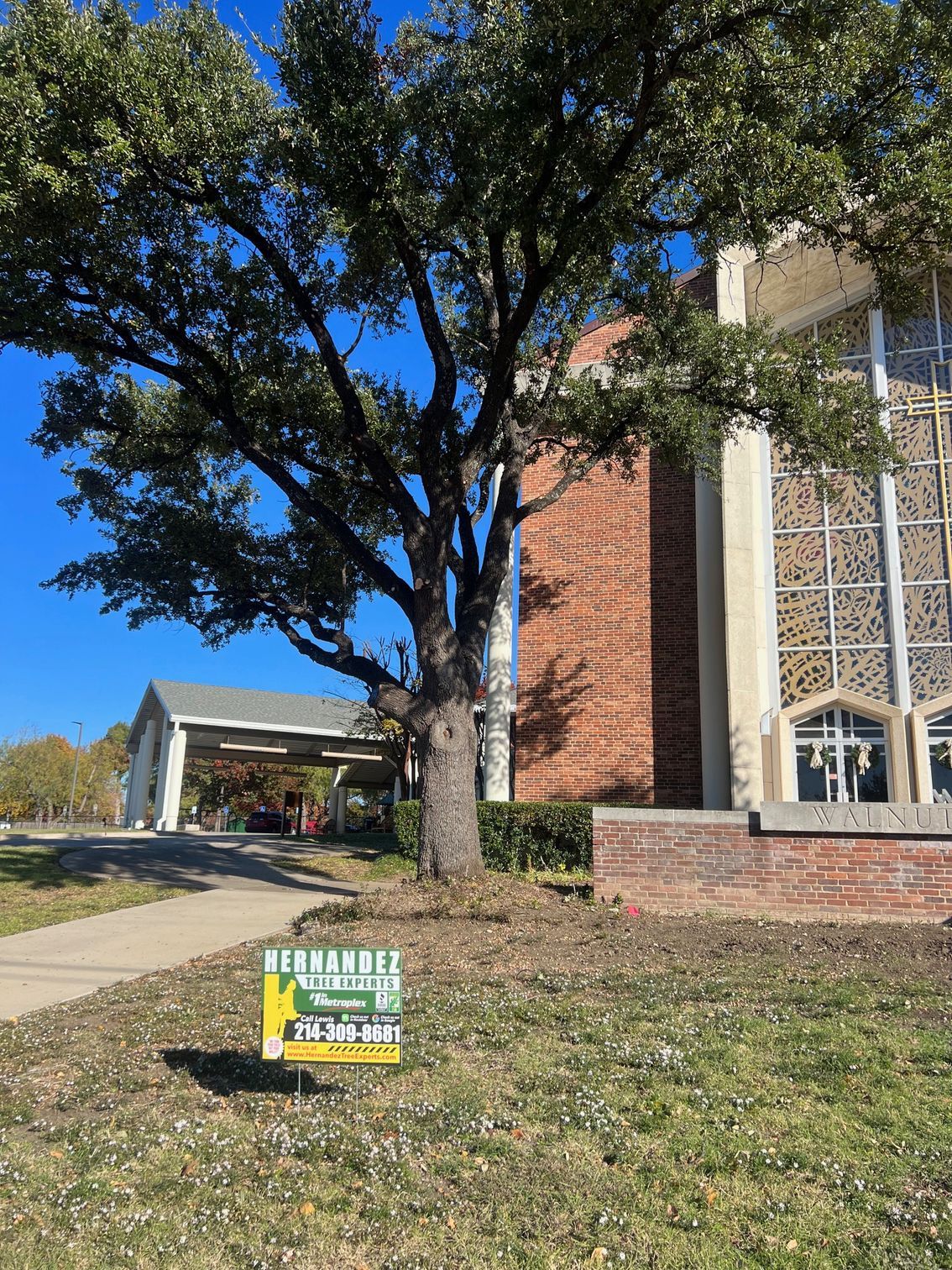A sign is sitting in the grass in front of a church.