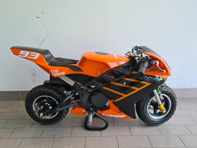 Motocicletta da corsa arancione e nera su un cavalletto, vista laterale in interni, con il numero 93 sulla coda.