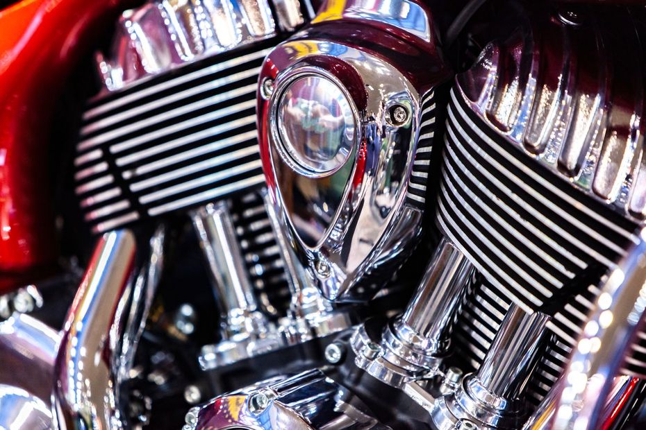 Primo piano di un motore di motocicletta cromato con dettagli rossi e strisce decorative.
