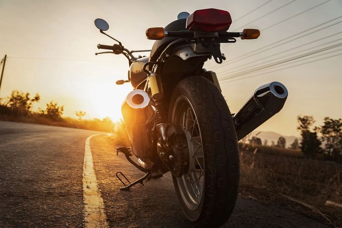 Motocicletta parcheggiata su una strada al tramonto, con il sole basso sull'orizzonte.