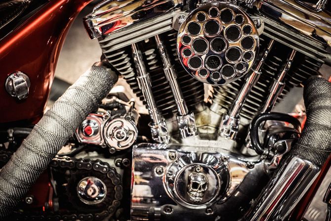 Primo piano di un motore di motocicletta cromato con pannelli della carrozzeria rossi e tubi flessibili intrecciati.