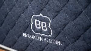 Quilted dark gray mattress cover with Brooklyn Bedding logo and “BB” emblem embroidered in white