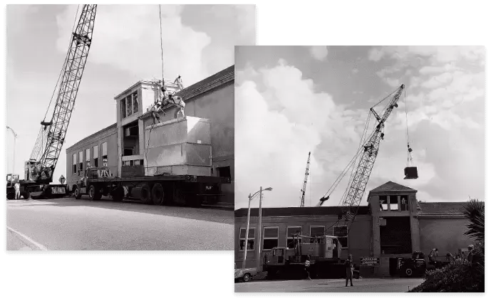 Two cranes lifting objects onto and off of a building, likely construction or demolition.