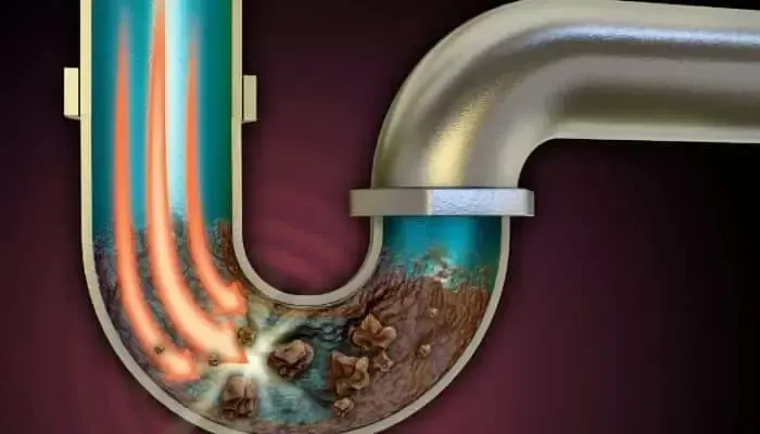 Cross-section of a curved pipe showing buildup, with water flow depicted in blue and orange.