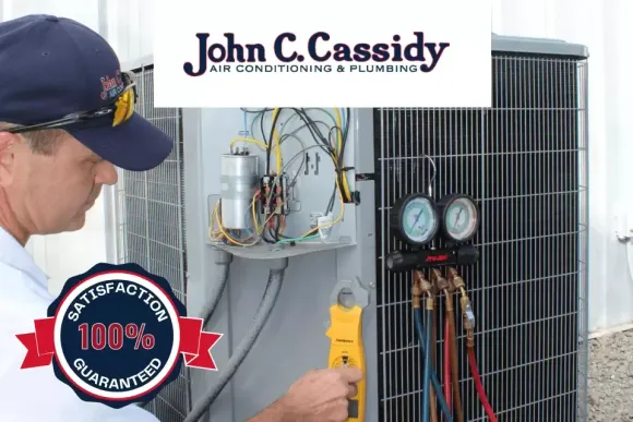 HVAC technician working on an air conditioner with gauges. 