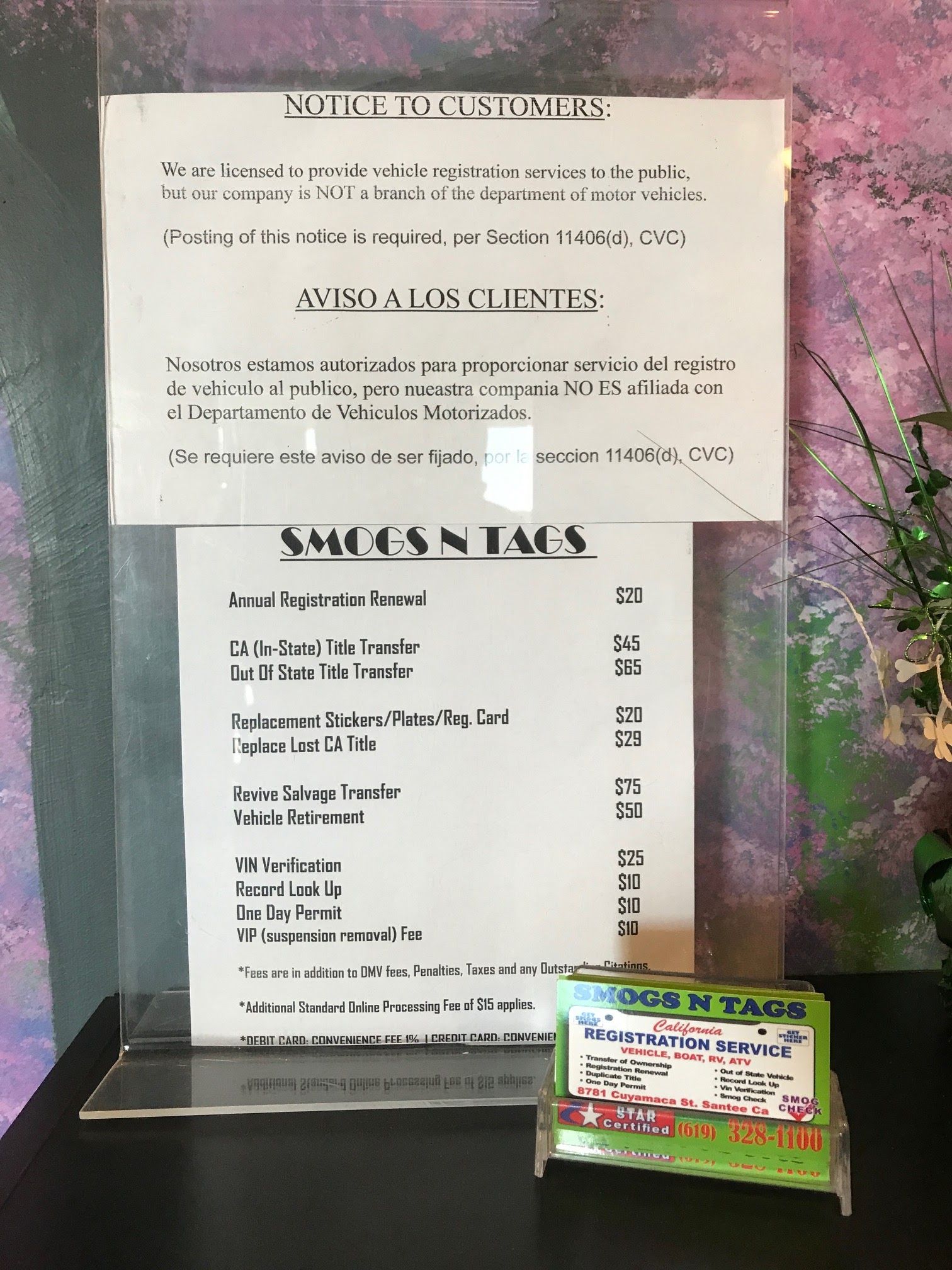 Menu sign on a glass door with a small colorful placard at the bottom.