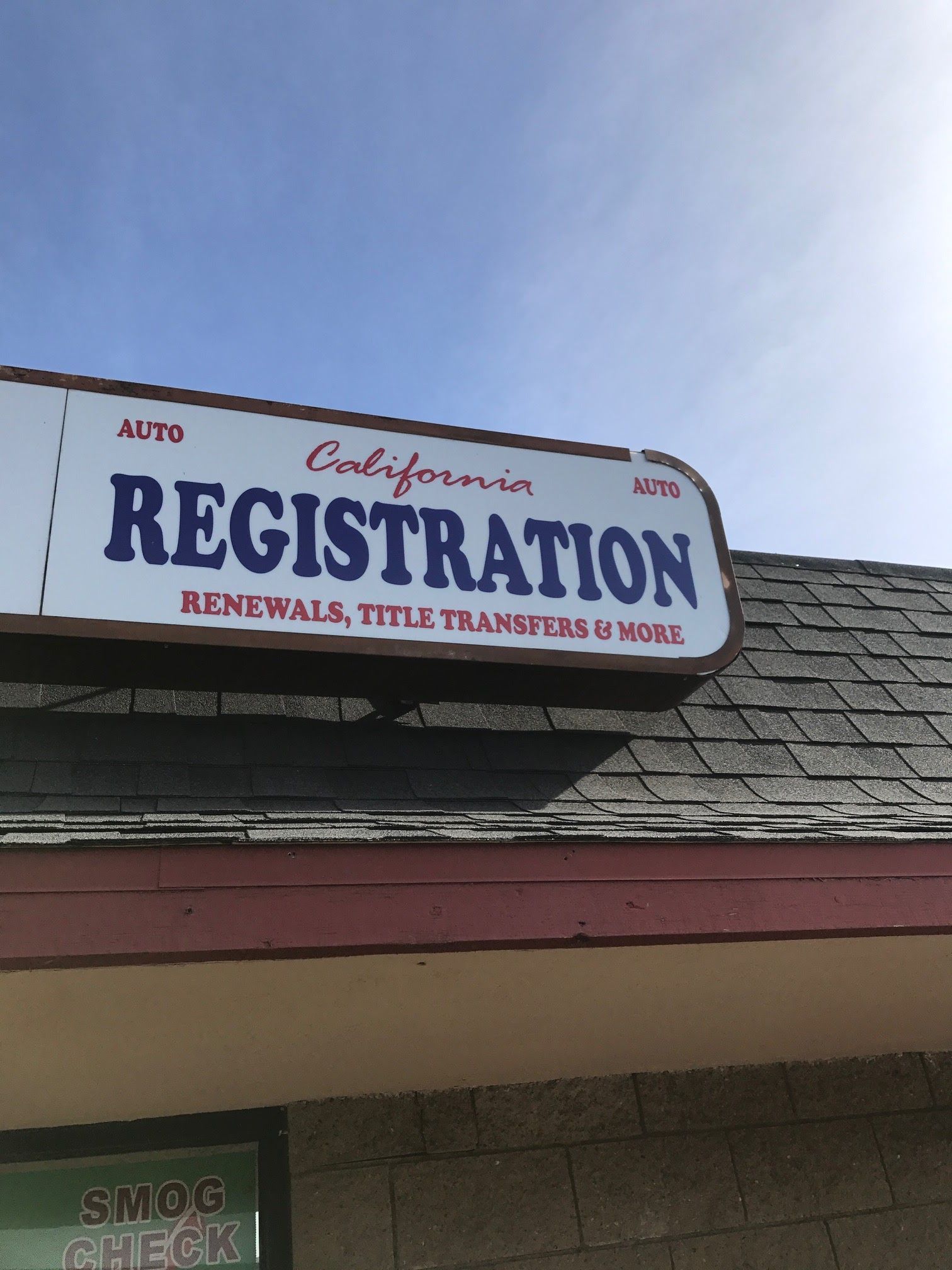 Storefront sign reading “Registration” above a roof, with blue sky in the background