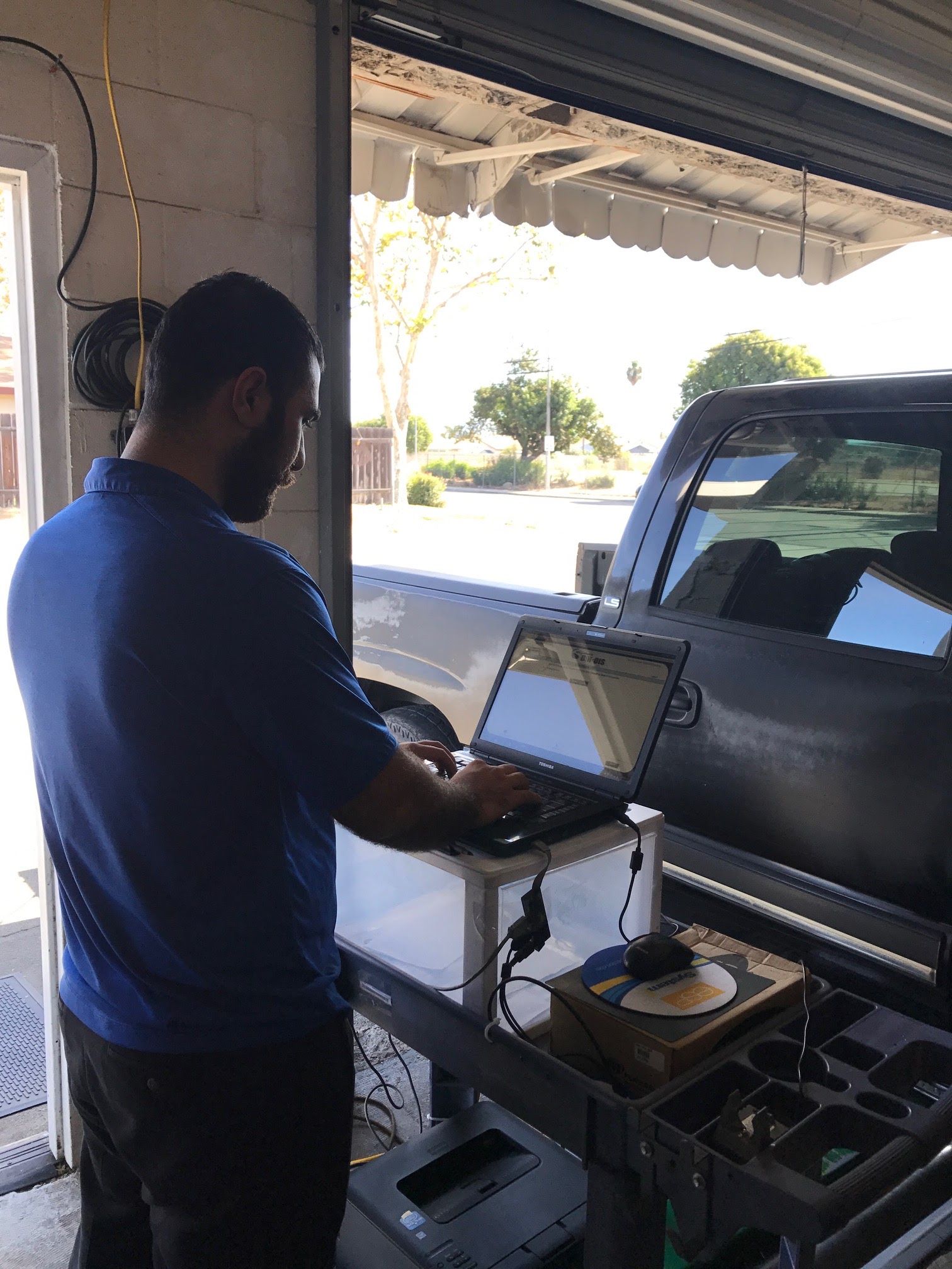 Person using a laptop beside a pickup truck in a garage or carport