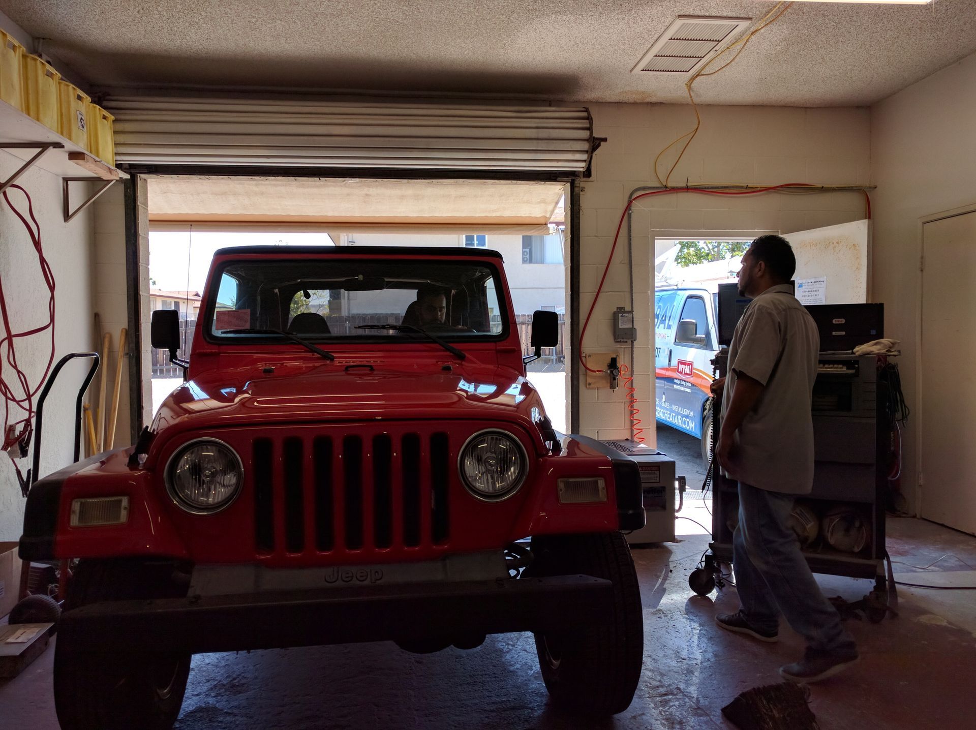 Red Jeep in a garage with a person standing by the open side door