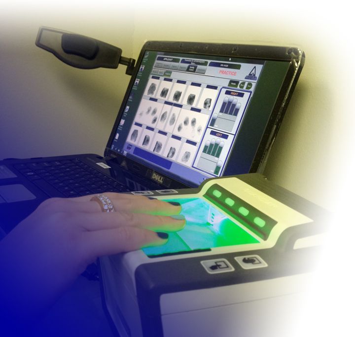Hand using a touchscreen device beside a laptop displaying a control panel interface