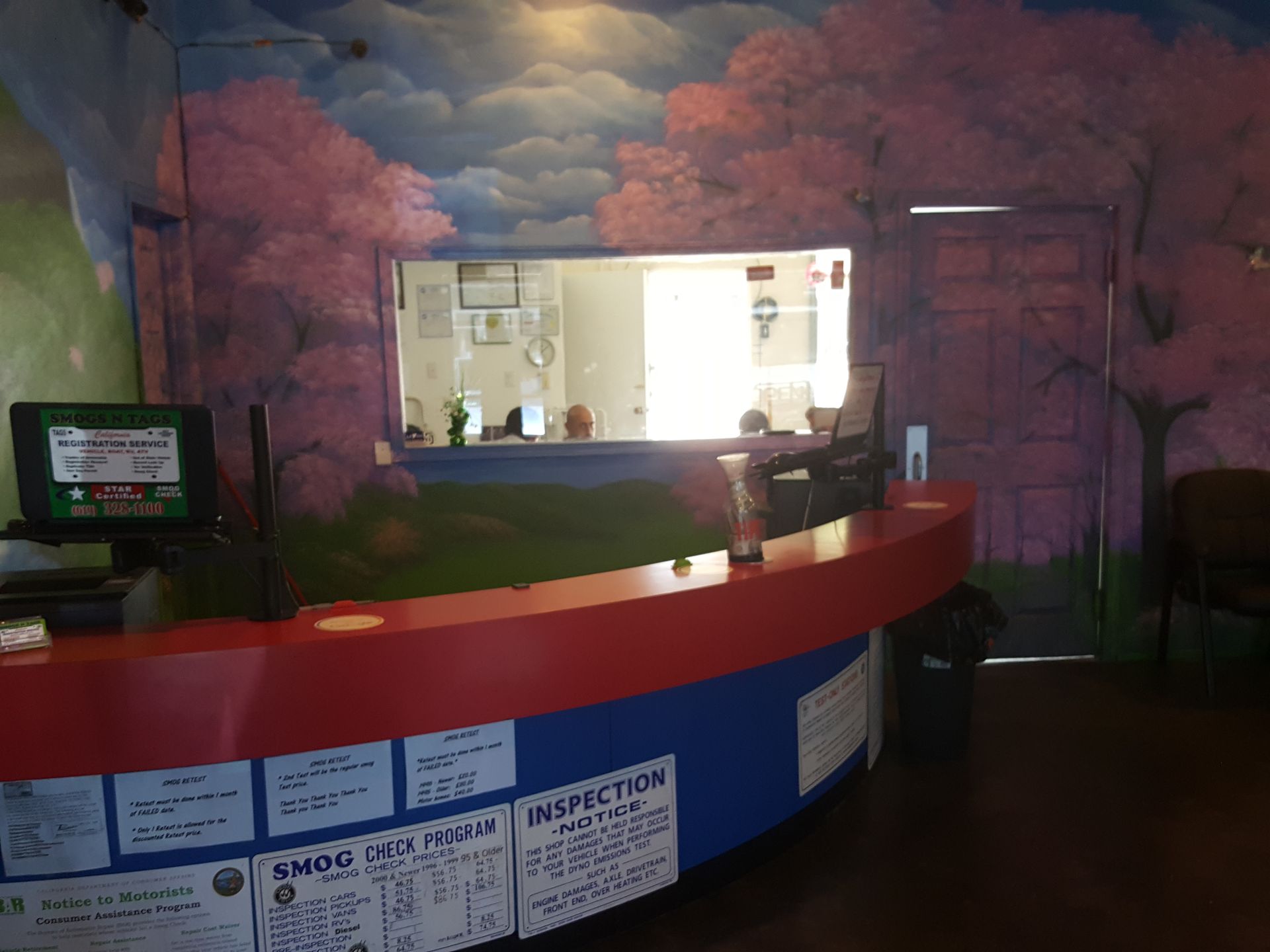 Reception desk with a purple mural wall and bright service window behind it