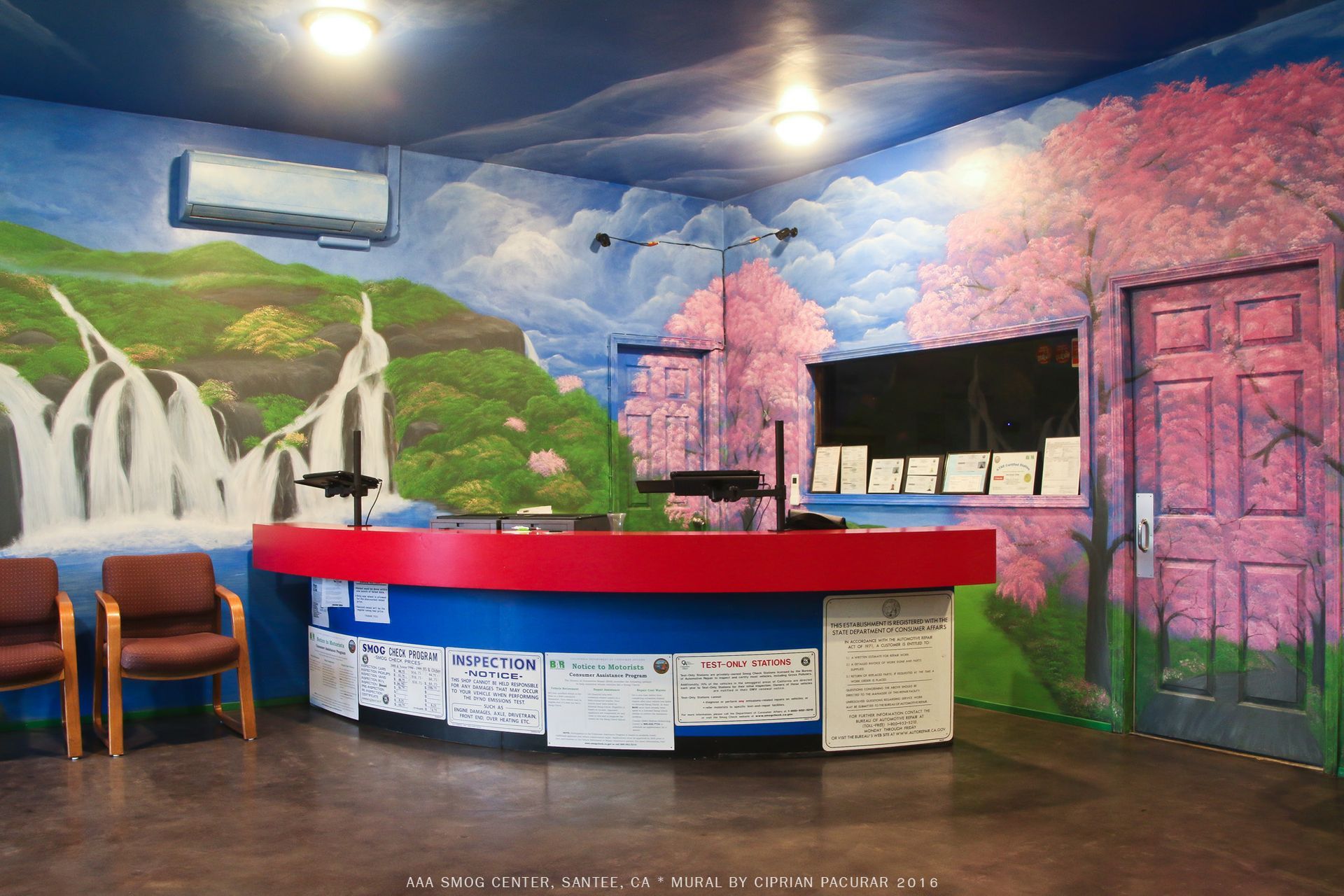 Colorful mural backdrop with a curved red-and-blue reception desk and chairs in a small lobby