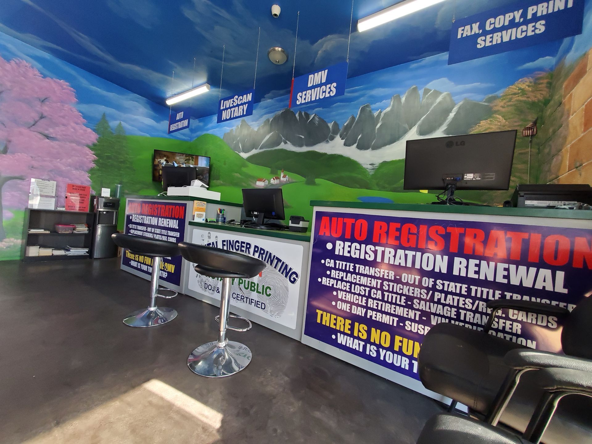 Auto registration and renewal service counter with signs, computer monitors, and a painted mountain mural
