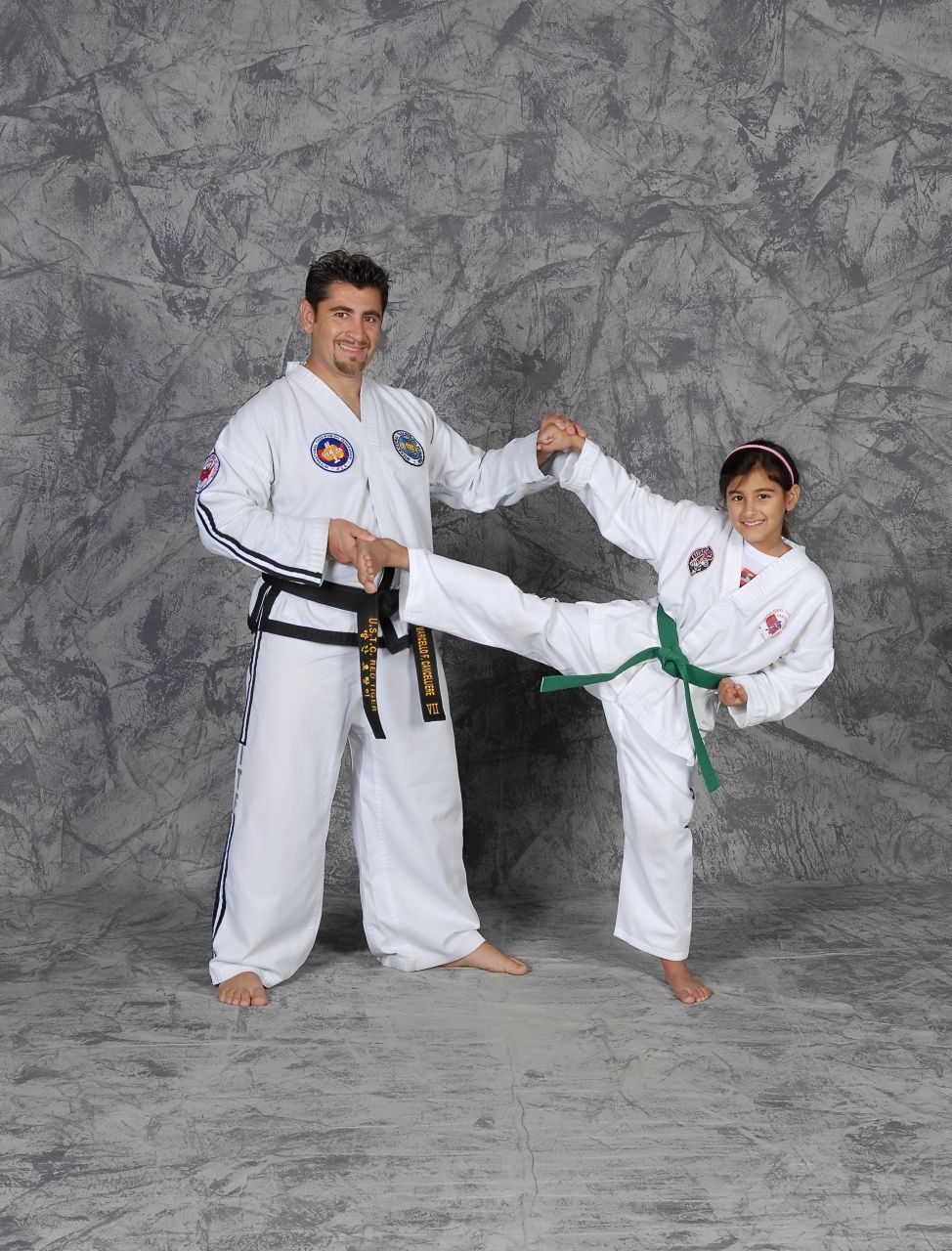 Children in white martial arts uniforms stand in a dojo during class instruction.
