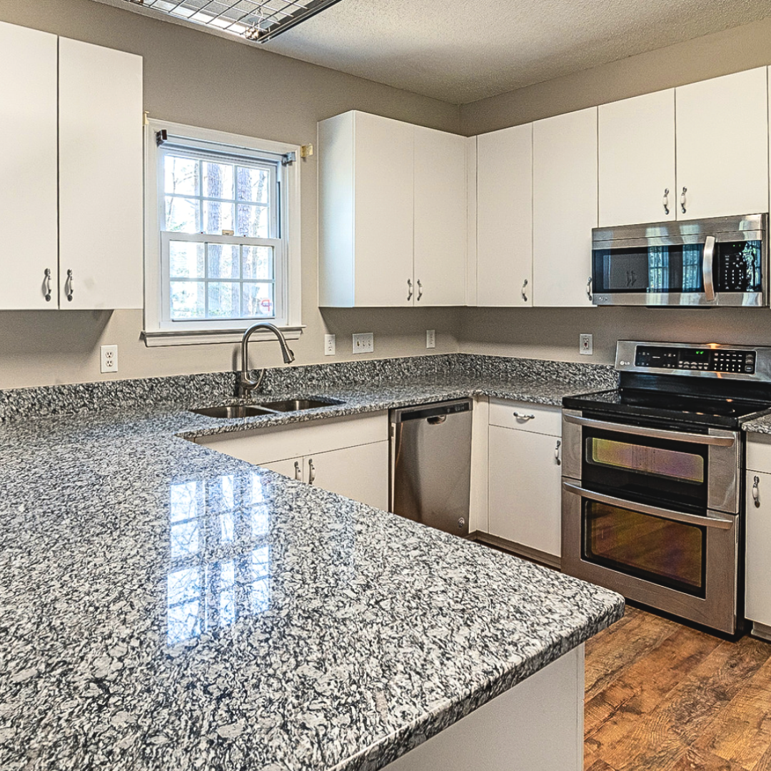 A kitchen with three bar stools and a stainless steel refrigerator