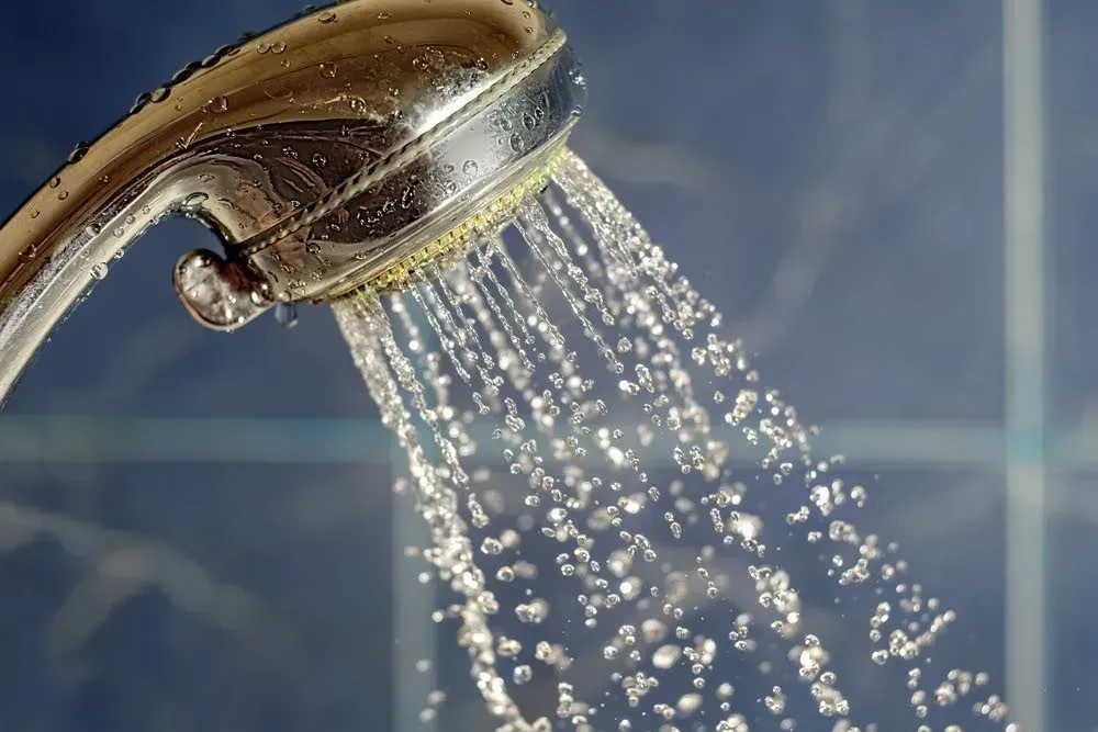A close up of a shower head with water coming out of it
