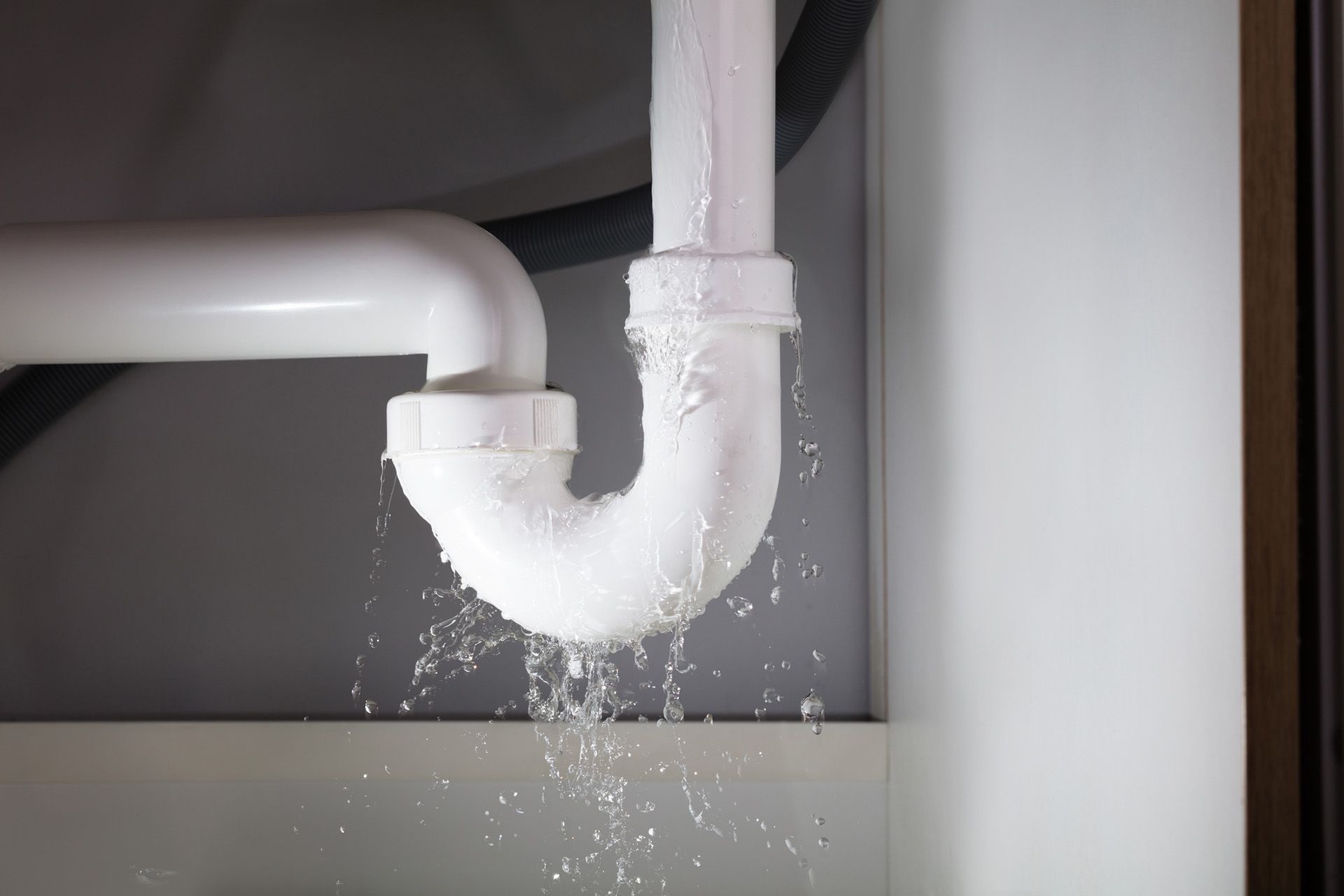 A sink pipe is leaking water under a sink