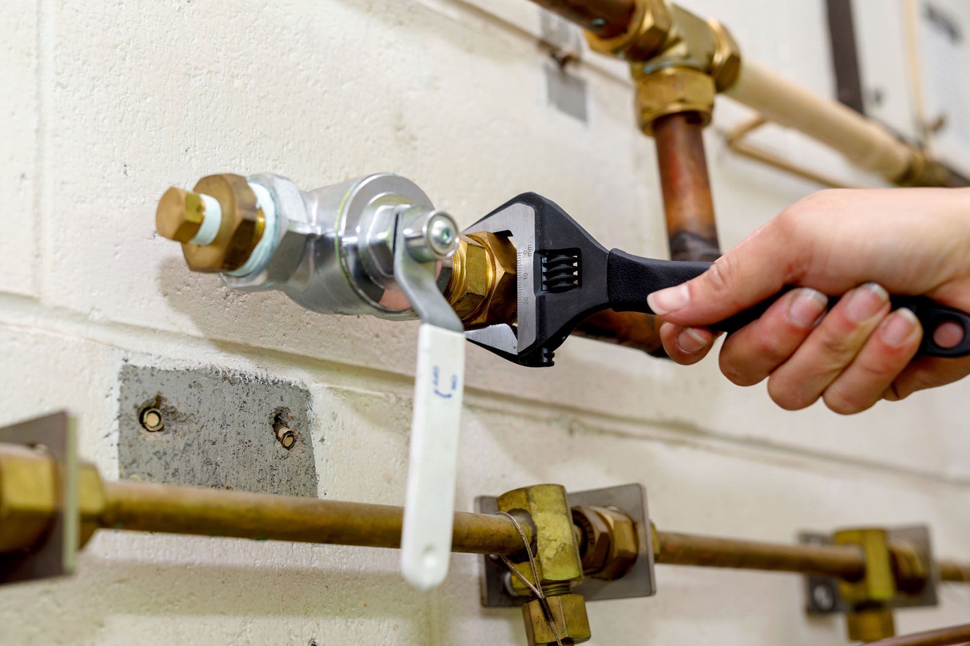 A person is fixing a gas pipe with a wrench