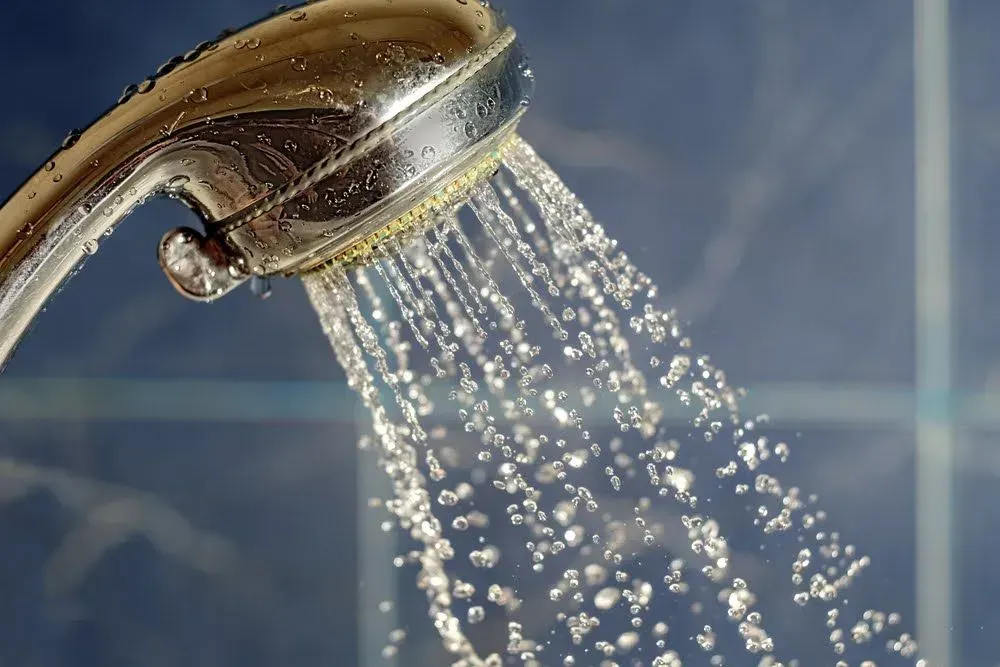 A close up of a shower head with water coming out of it