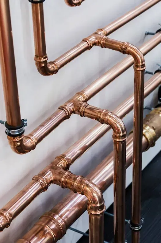 A bunch of copper pipes are connected to each other on a wall.