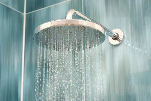 Water is coming out of a shower head in a bathroom.