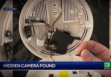 A person is holding a hidden camera inside of a smoke detector.