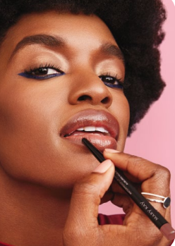 Primer plano de una persona aplicándose delineador de labios con un lápiz negro.