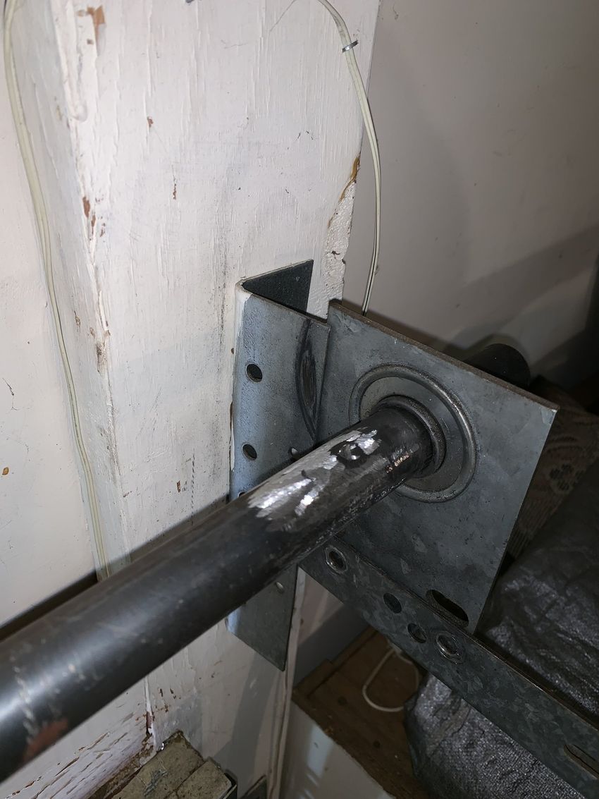 Metal shaft in a wall-mounted bracket with bearings, close-up of hardware installation