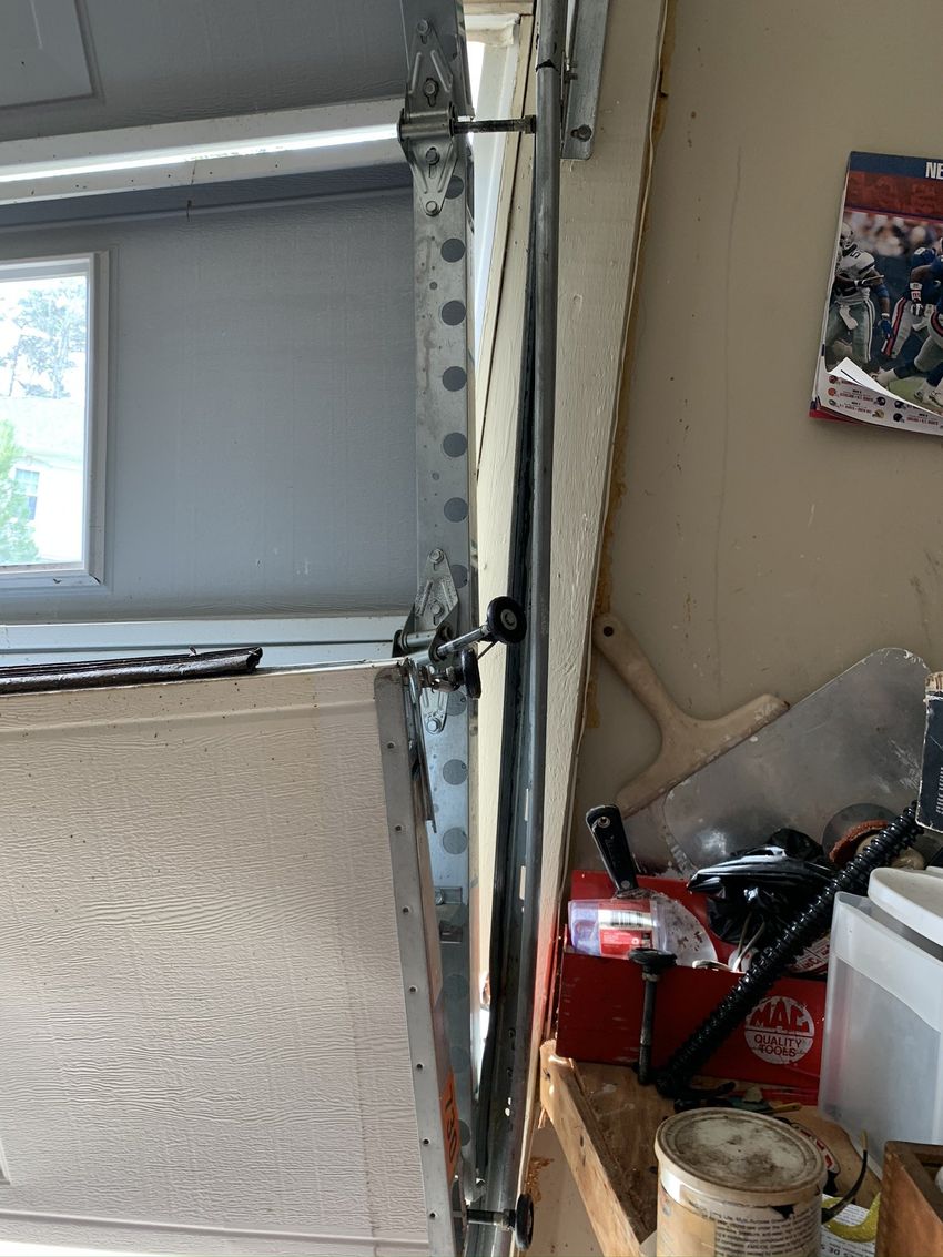 Garage interior with open door track, window, and cluttered shelf with tools and a red fire extinguisher